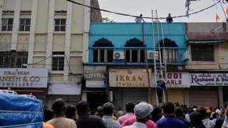 Gente mirando mientras bomberos realizan tareas de rescate en un edificio tras un incendio en Hyderabad, India, el domingo 18 de mayo de 2025.